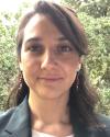 Dr. Rabanes, a woman with shoulder-length wavy black hair and medium-light skin is smiling and looking into the camera.
